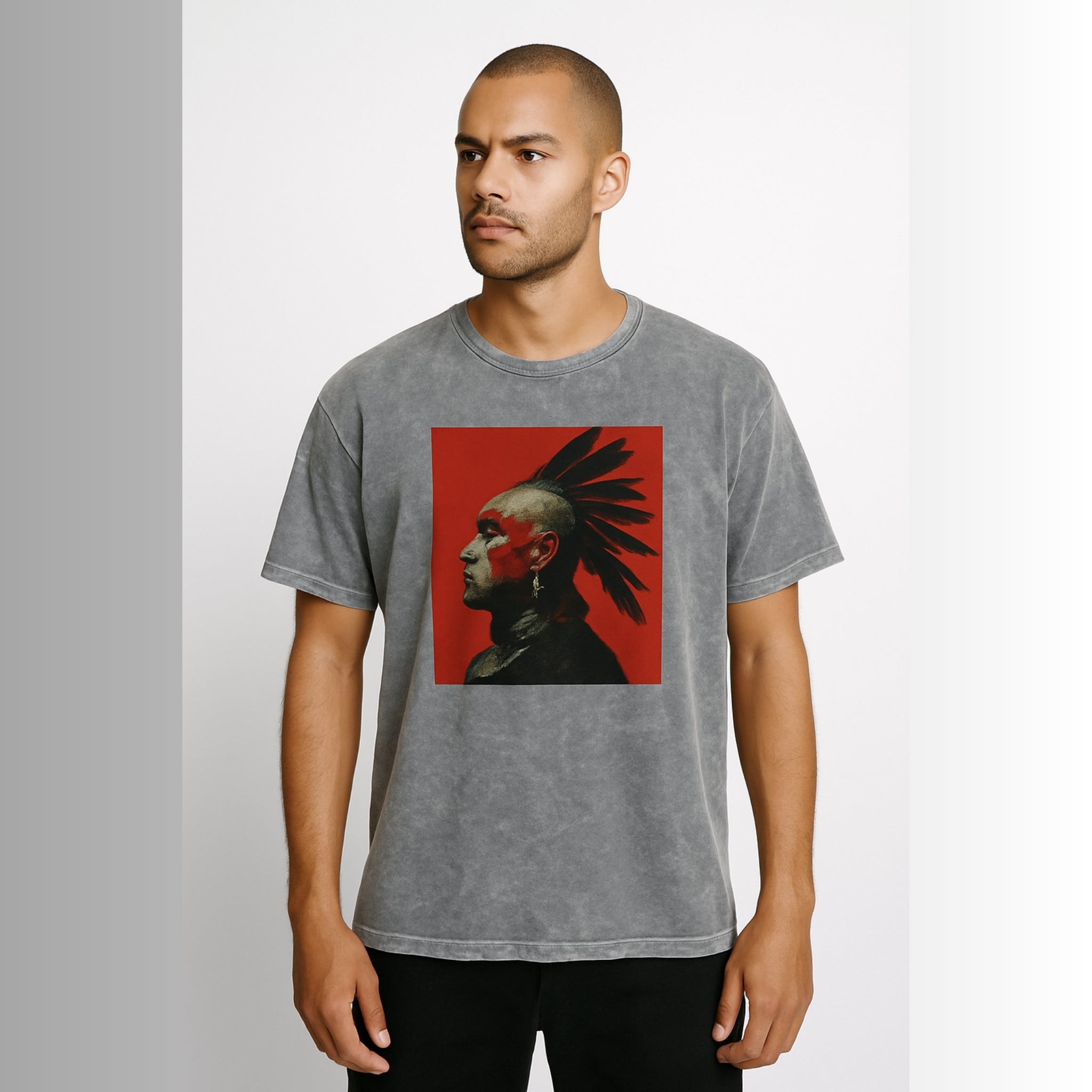 Model wearing Breakin' Atoms "Warrior’s Legacy Tee," a washed charcoal t-shirt featuring a striking red-and-black profile portrait of an Indigenous warrior with traditional war paint and feathered headdress — honoring cultural strength and legacy through bold graphic streetwear.