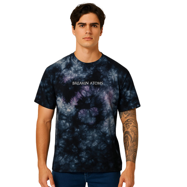Male model wearing Breakin' Atoms Marble Logo Tee in black and purple tie-dye with centered logo text