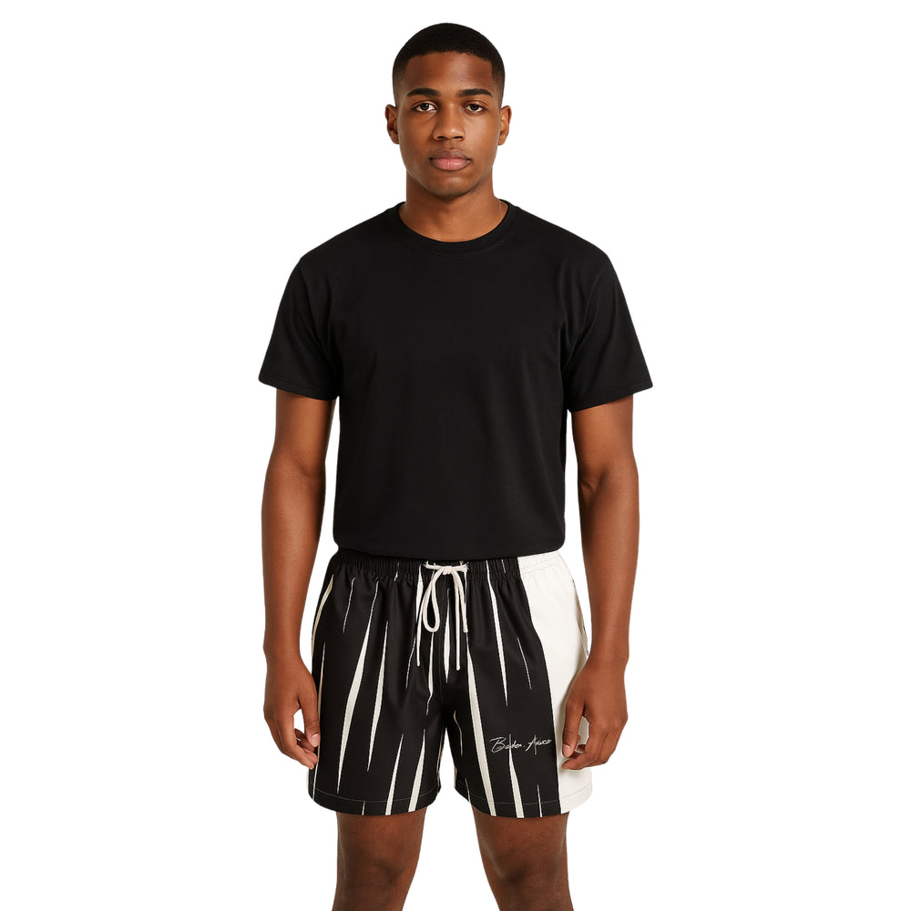 Model wearing Breakin' Atoms "Monochrome Strike Shorts," black and white split-panel shorts with vertical stripe detailing and signature branding — combining clean minimalism with sharp streetwear edge. — Breakin Atoms premium streetwear