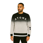 Model wearing Breakin' Atoms "Pixel Dusk Knit," a black-to-gray gradient sweater with pixelated dot fade, bold "ATOMS" typography, and parachuting silhouette graphic on the sleeve — blending cozy knitwear with streetwear flair. thumbnail 1